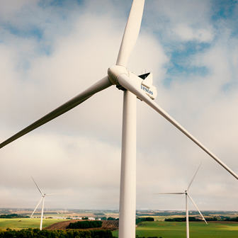 Wind turbine against a blue sky viewed from below