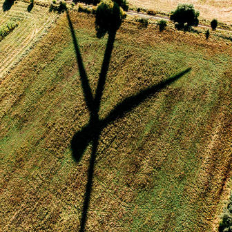 Aerial shadow of a wind turbine blade cast over agricultural fields